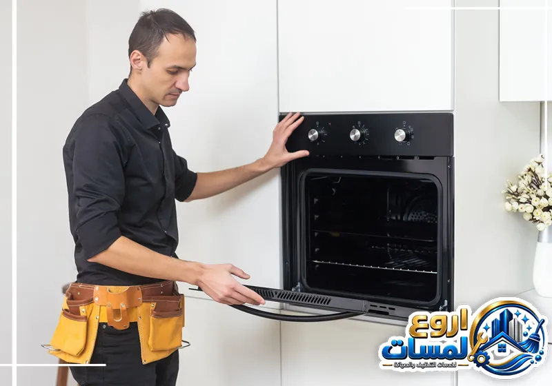 صيانة افران ميتاج بالرياض | شركة اروع لمسات فني صيانة يفحص فرن جنرال اليكتريك المدمج داخل المطبخ لإصلاح الأعطال.
